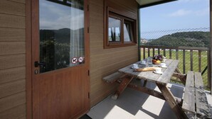 A wooden cabin with a sliding glass door, a small window, and a picnic table with food and drinks. - Bungalow For 4, Terrace - Zumaia, Spain (Zumaya)