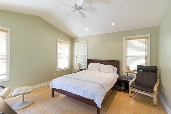 A bedroom with a bed, bedside tables, a chair, and a ceiling fan. - Sojourn on Cherry Lane (Austin)
