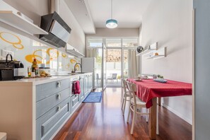 Een moderne keuken met een eethoek, houten vloeren en uitzicht door glazen deuren.