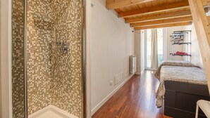 Ein Zimmer mit Dusche, Holzbalkendecke, Heizkörper und einem Bett.