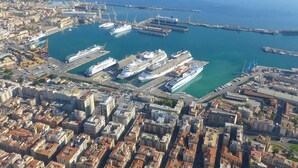 Luftaufnahme einer Küstenstadt mit einem Yachthafen, Gebäuden und blauem Meer.