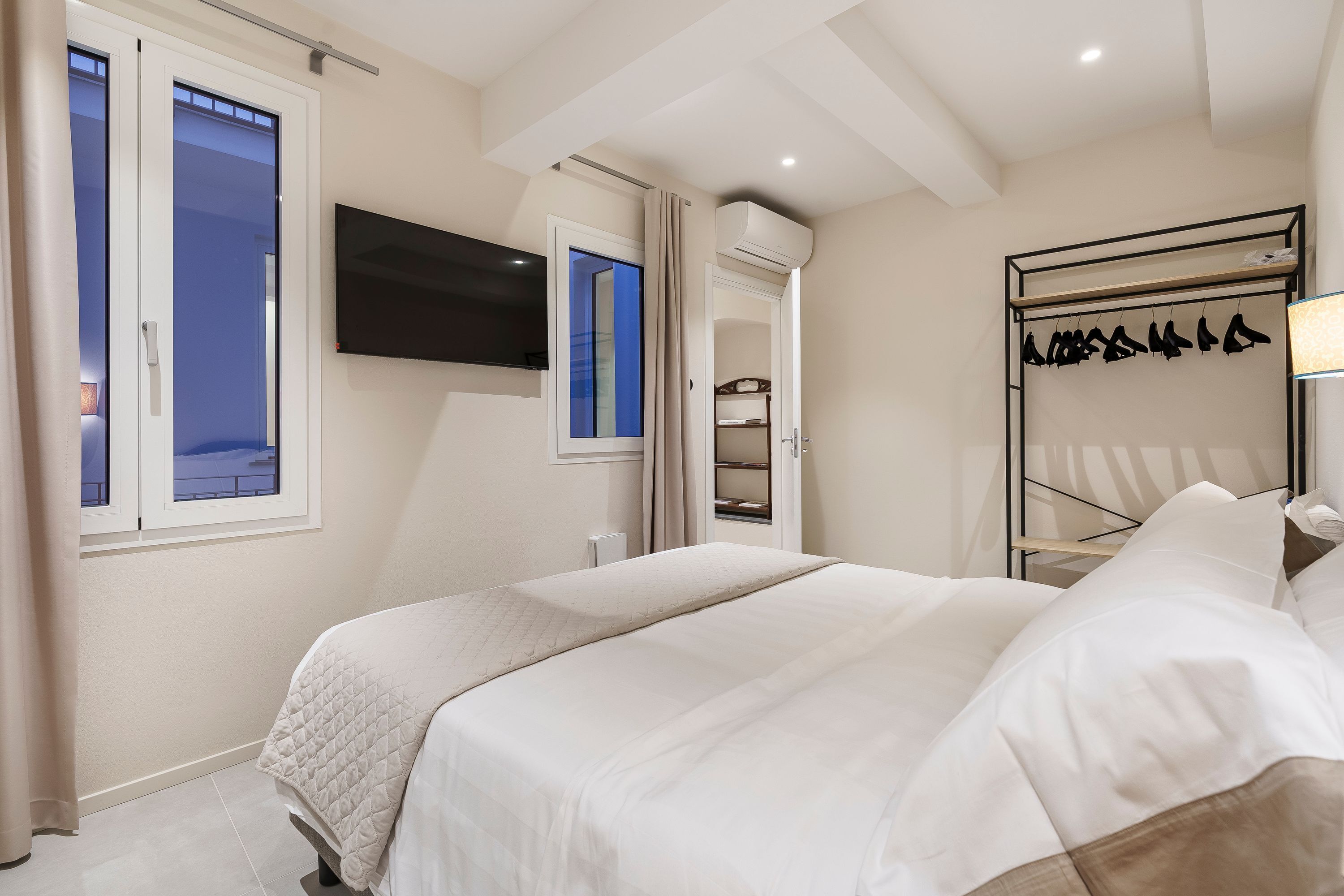 A bedroom with a bed, a TV, a wardrobe, and a window.