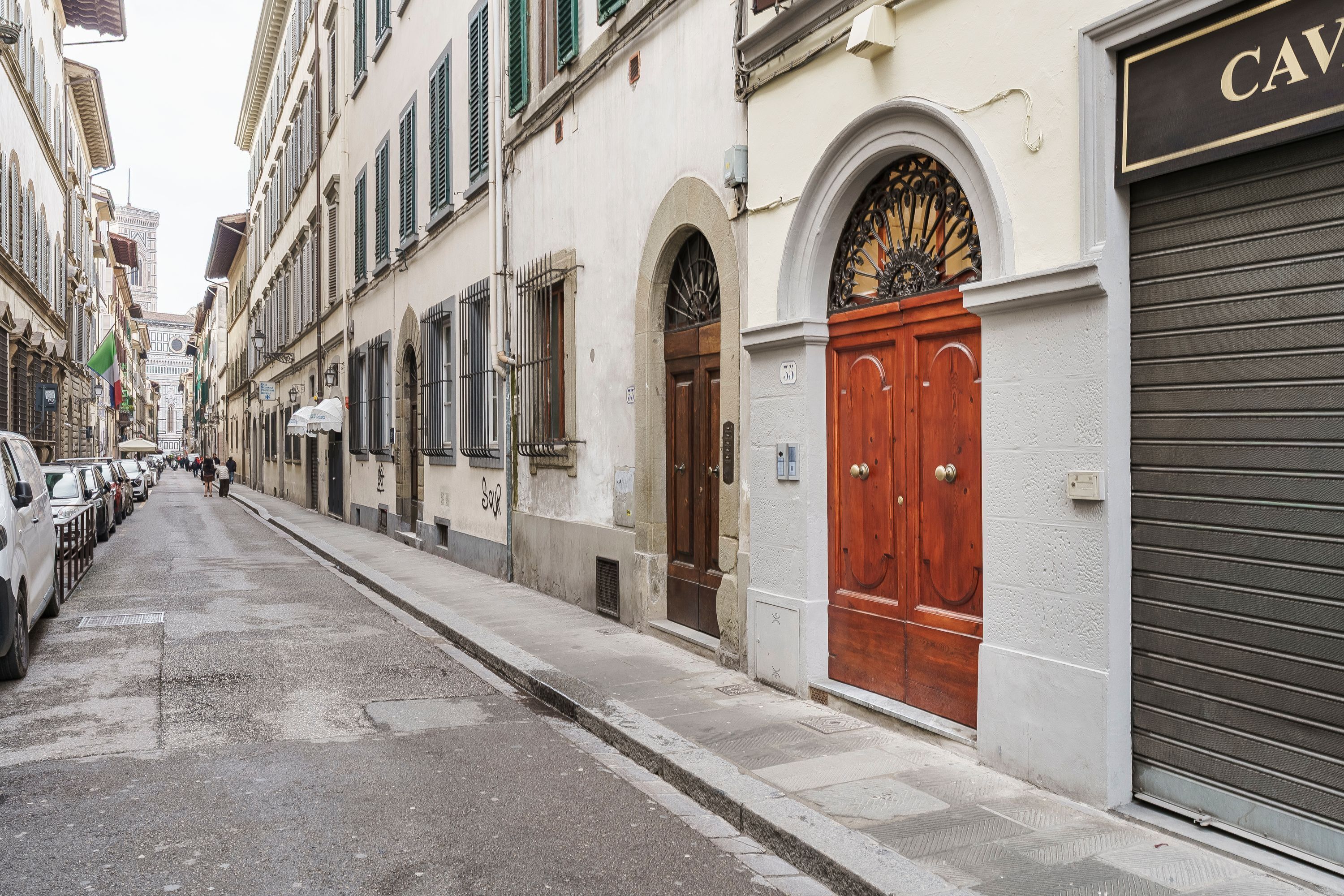 Une rue étroite bordée d’immeubles, une porte en bois et une porte de garage fermée.
