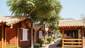 A row of wooden cabins with tiled roofs, arranged along a paved path with small trees and shrubs. - 52m² Chalet with Terrace in Benicàssim for 4 people (Benicasim)