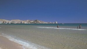 A beach with clear water, a sandy shore, and buildings in the background. - 52m² Chalet with Terrace in Benicàssim for 4 people (Benicasim)