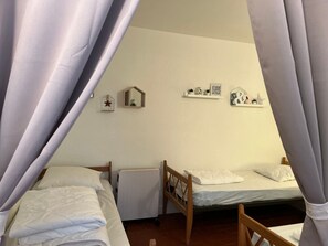 A room with two single beds, a radiator, and wall decorations including a star, a mirror, and a shelf with items. - Renovated T3 Apartment near slopes, 8-10 pers (Enchastrayes)