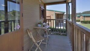 Una terraza de madera con mesa y sillas, con vistas a un paisaje verde.