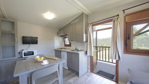Una cocina compacta con comedor, un televisor montado en la pared y un balcón con vistas al exterior.