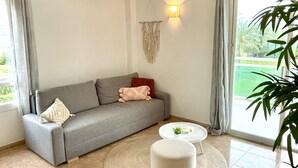 Un salon avec un canapé gris, une petite table ronde et une plante en pot.