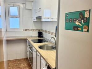 Una cocina moderna con armarios blancos, un lavamanos de acero inoxidable y una cafetera.