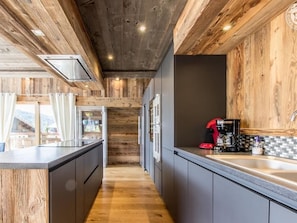 A modern kitchen with wooden accents, a built-in oven, and a coffee machine. - Luxury Chalet in Les Gets with Jacuzzi, Wifi & Parking (Les Gets)