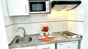 A compact kitchen with a microwave, stove, sink, and white cabinets. - Beachfront Loft with A/C and Pool, Near Port Aventura, Salou (Salou)