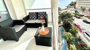 A balcony with a black sofa, patterned cushions, and a vase with flowers. - Beachfront Loft with A/C and Pool, Near Port Aventura, Salou (Salou)
