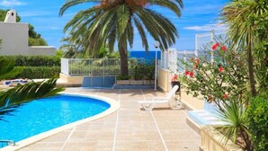 A swimming pool with a curved edge, surrounded by a tiled deck and a palm tree. - Beachfront Loft with A/C and Pool, Near Port Aventura, Salou (Salou)