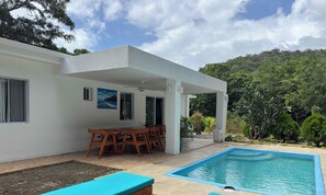 Une maison moderne dotée d’une piscine, d’un coin repas et d’une terrasse couverte.