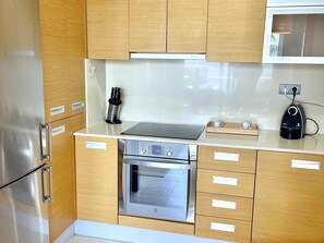 A modern kitchen with stainless steel appliances, wooden cabinets, and a built-in microwave. - Seafront apartment with pool and parking in Miami Playa (Miami Playa)