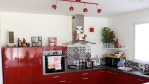Eine moderne Küche mit roten Schränken, einem eingebauten Backofen und einer roten Pendelleuchte.