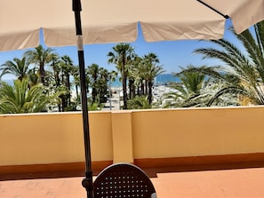 Een balkon met uitzicht op palmbomen en de zee.