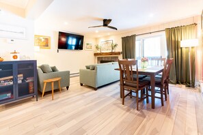 Una sala de estar con un sofá, una mesa de comedor con sillas, un televisor y una chimenea.