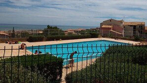 A swimming pool with a view of the sea and buildings in the background. - Charming Apartment in Saint Pierre La Mer with Pool and Parking (Fleury-Saint-Pierre-la-Mer)