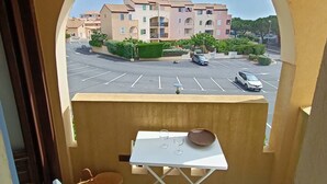 A balcony with a view of a parking lot and a building with multiple floors and balconies. - Charming Apartment in Saint Pierre La Mer with Pool and Parking (Fleury-Saint-Pierre-la-Mer)