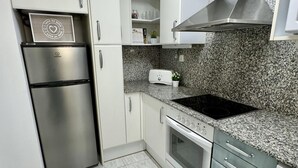 Una cocina moderna con electrodomésticos de acero inoxidable, encimeras de granito y muebles de color blanco.