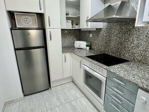A modern kitchen with stainless steel appliances, granite countertops, and white cabinetry. - Beautiful family apartment in Salou 1 min from the beach with terrace and private parking (Salou)