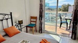 Una habitación de hotel con cama, una silla, una mesa y un balcón con vistas.