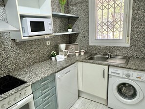 A compact kitchen with a microwave, coffee maker, sink, dishwasher, and washing machine. - Beautiful family apartment in Salou 1 min from the beach with terrace and private parking (Salou)