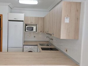 Una cocina compacta con microondas integrado, lavadora y lavaplatos.