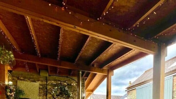 Un patio al aire libre con una mesa redonda, sillas, una parrilla y un tapete estampado.