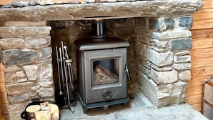 Una chimenea de piedra con estufa de leña, un banco de piedra y un repisa de chimenea.