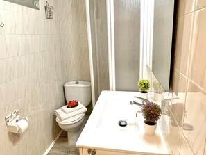 Ein Badezimmer mit Toilette, Waschbecken und zwei Blumentöpfen.