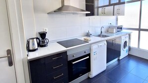 Moderni keittiö, jossa on sisäänrakennettu uuni, astianpesukone ja kahvinkeitin.