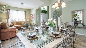 Comedor con una mesa de vidrio preparada para cuatro personas, rodeado de sillas de metal.
