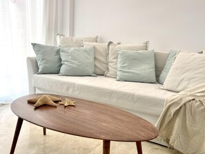 A living room with a beige sofa, multiple cushions, a wooden coffee table, and a starfish decoration. - Air-conditioned apartment with pool in Salou, near beach and Port Aventura (Salou)