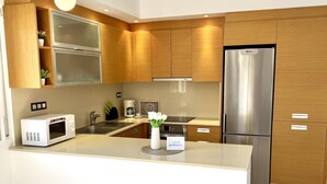 A modern kitchen with wooden cabinets, a stainless steel refrigerator, a microwave, and a coffee maker. - Beautiful beachfront apartment with pool and private parking (Miami Playa)