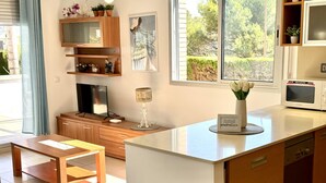 A modern kitchen with a central island, wooden cabinetry, a built-in microwave, and a dining area with a bench. - Beautiful beachfront apartment with pool and private parking (Miami Playa)