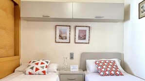 A hotel room with two beds, a wardrobe, a bedside table with a vase, and two framed pictures on the wall. - Family Seafront Apartment - Pool, Air Conditioning, Terrace (Cambrils)