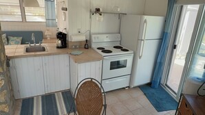 A compact kitchen with a stove, refrigerator, and sink. There is a chair and a small rug. - On the beach, Private path to the ocean beach. (Cat Island)