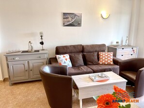 Un salon moderne avec un canapé en cuir marron, une table basse blanche et un meuble gris. Un tableau est accroché au mur et un objet décoratif est posé sur le meuble.