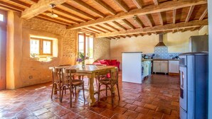 A rustic kitchen with exposed wooden beams, a stone wall, and a tiled floor. - RURAL ECOGITE LA CLE DES CHAMPS (Peyrelongue-Abos)
