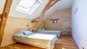 A small, cozy attic bedroom with two beds, a skylight, and a small table. - RURAL ECOGITE LA CLE DES CHAMPS (Peyrelongue-Abos)