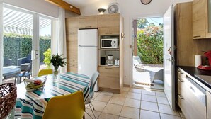 Eine moderne Küche mit Holzschränken, einem Kühlschrank, einer Mikrowelle und einem Essbereich mit gestreiftem Tischläufer und Stühlen.