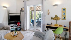 Ein Wohnzimmer mit Fernseher, einer Couch und einem Essbereich mit Stühlen und Tisch.