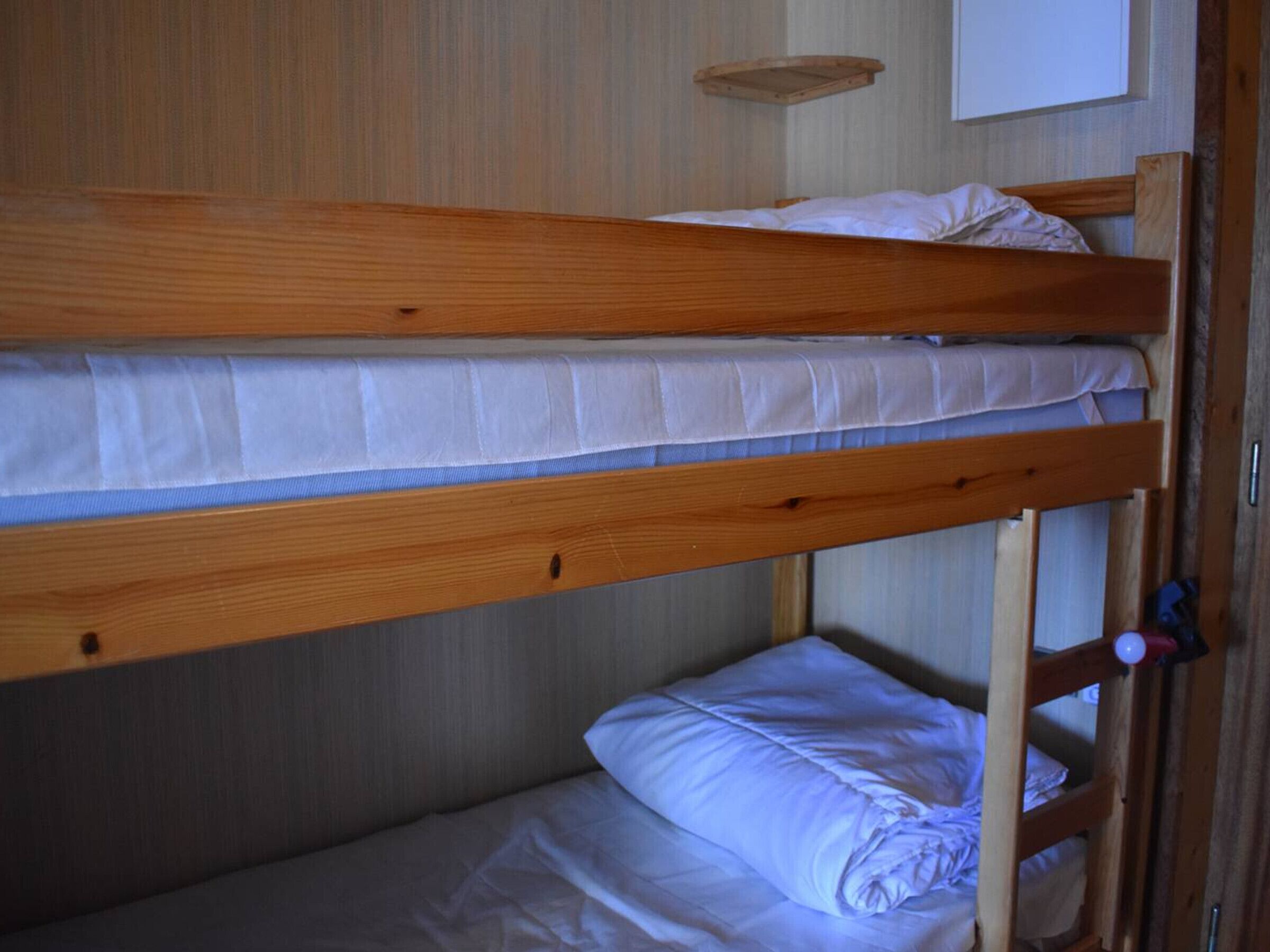 A bunk bed with two levels, each with a mattress and pillows.