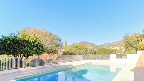 A swimming pool with a white fence, surrounded by trees and a mountain in the background. - Provençal Mazet with Pool, Pets Welcome, Secure Parking (Le Lavandou)