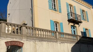 A building with a balcony, a car parked in front, and a gate. - Cozy townhouse, port view, in the heart of Sauzon (Sauzon)