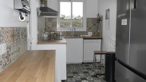 A compact kitchen with a wooden countertop, a built-in dishwasher, and a stainless steel refrigerator. - Cozy townhouse, port view, in the heart of Sauzon (Sauzon)