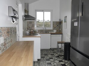 A compact kitchen with a wooden countertop, a built-in dishwasher, and a stainless steel refrigerator. - Cozy townhouse, port view, in the heart of Sauzon (Sauzon)